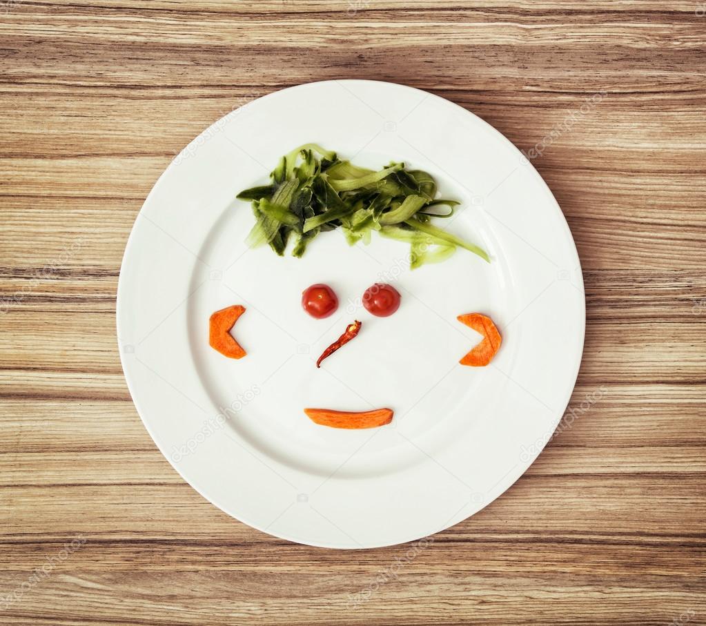 Vegetable face made of cucumber, chilli, tomatoes and carrot on 