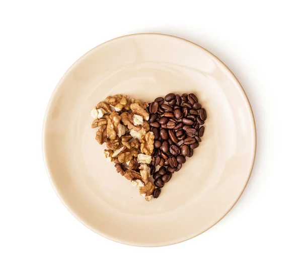 Form hjärtat av kaffebönor och skalade valnötter på plattan, Val — Stockfoto
