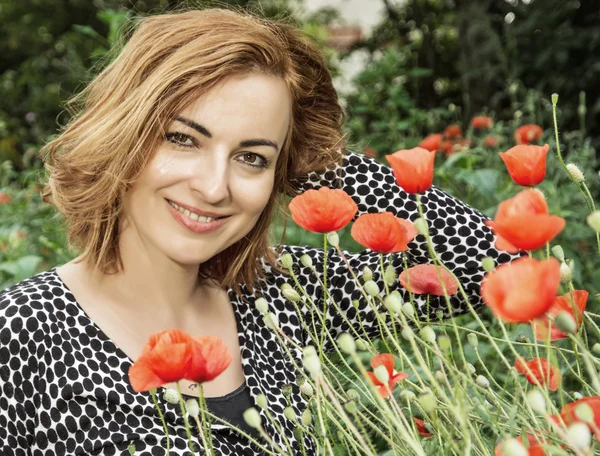 Young positive caucasian brunette and corn poppy flowers — Stock Photo, Image