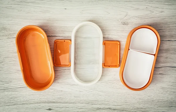 木製の背景にオレンジ色の折りたたみ式プラスチック製食品ボックス — ストック写真