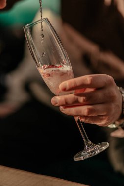 Sevgililer Günü kutlamanız kutlu olsun. Kırmızı kalp şeklindeki konfetiyle şampanya dolduran adam. Bardakta aşk iksiri. Kapat.