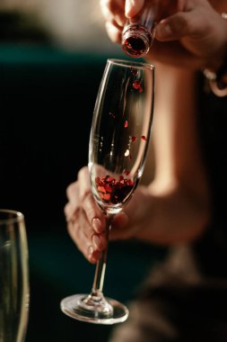 Sevgililer Günü kutlamanız kutlu olsun. Adam kadınlara aşk iksiri dolduruyor. Boş şampanya kadehi. Kırmızı Kalp cam konfeti şeklinde. Kapat.