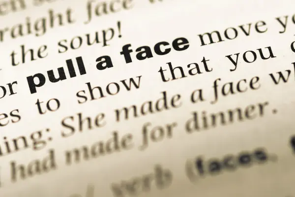 Close up of old English dictionary page with word pull a face — Stock Photo, Image