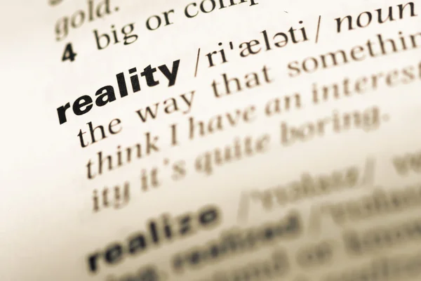 Close up of old English dictionary page with word reality — Stock Photo, Image