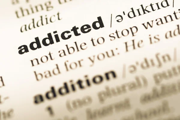 Avvicinamento della vecchia pagina del dizionario inglese con word addicted — Foto Stock