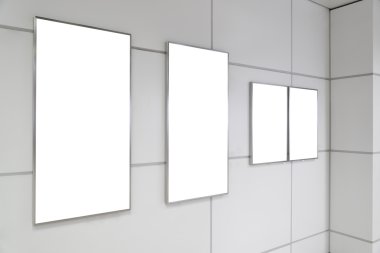 Four big vertical / portrait orientation blank billboard on white wall in public open space