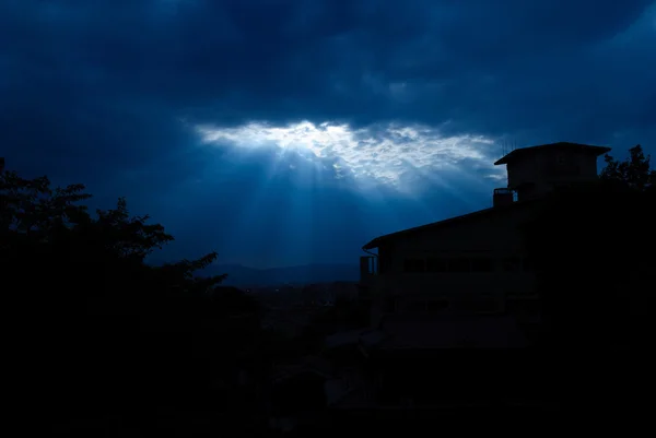 Light form the sky shining down on house / Crepuscular rays / Jesus light with house in deep blue sky