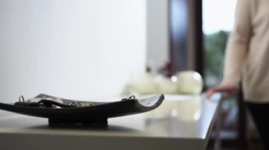 Kadın, eve gitmek için kişisel tepsiden anahtarları al.