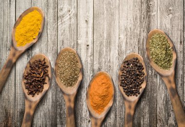 Masadaki tahta kaşıklarda çeşitli baharatlar var..