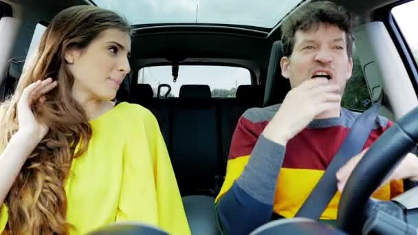 Мужчина и женщина делают смешные сумасшедшие лица в машине за рулем замедленной съемки — стоковое видео