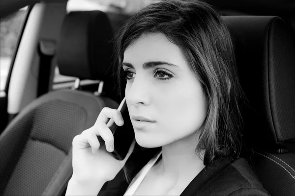 Grave giovane donna d'affari al telefono in auto ritratto in bianco e nero — Foto Stock