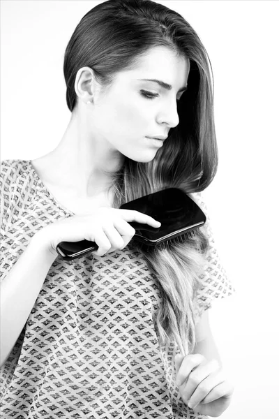 Zwart-wit portret van een modus die haar lange haren borstelen — Stockfoto