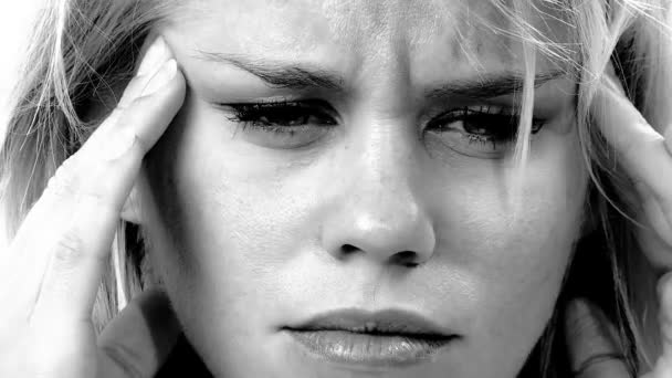 Sad blond woman at home sitting on sofa with strong headache tired black and white