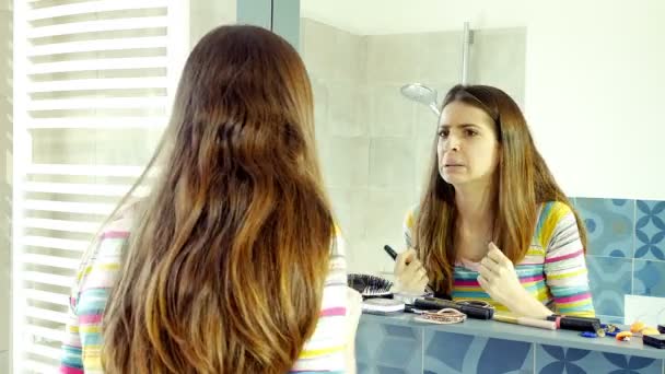 Krásná žena s dlouhými vlasy, pokrývající pupínek v obličej s make-upem ve hře koupelně zba — Stock video