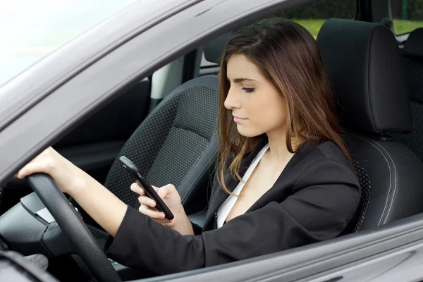 Zakelijke vrouw SMS bericht met mobiele telefoon zitten in de auto werken — Stockfoto