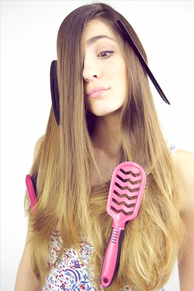 Jovem mulher fazendo cara engraçada com escovas e pente pau no cabelo — Fotografia de Stock