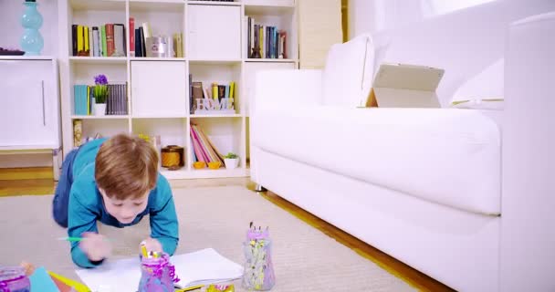 Happy kid in living room painting on book — Stock Video