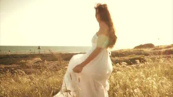 Красивая женщина перед океаном в кукурузном поле смотрит в камеру — стоковое видео