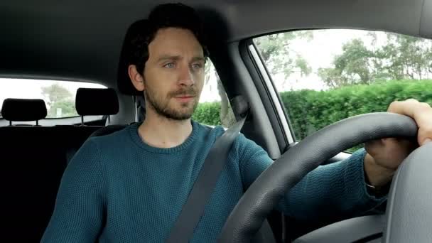 Красивый мужчина с голубыми глазами за рулем автомобиля улыбается 4K — стоковое видео
