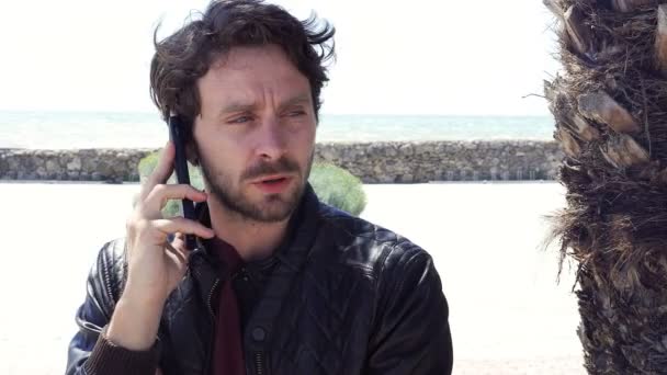 Un bell'uomo che parla al telefono davanti al carrello dell'oceano. — Video Stock