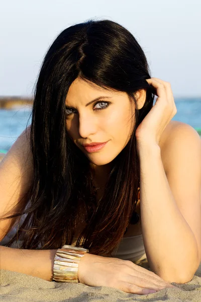 Fascinating model looking at camera, lying on the beach with ocean behind — Stock Photo, Image