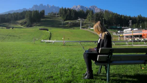 Красивая блондинка работает с ноутбуком в горах — стоковое видео