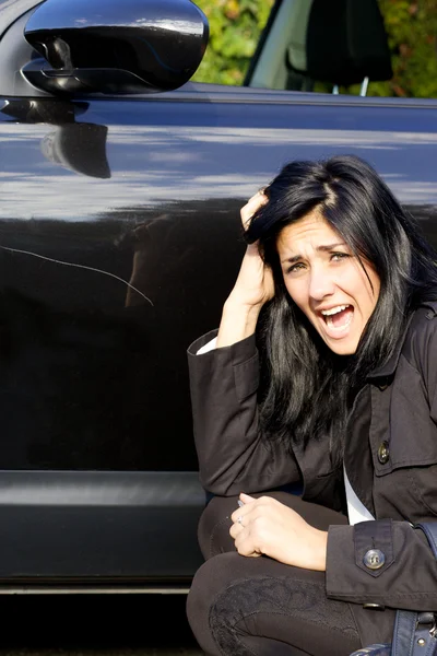 Женщина кричит сердито от царапанной машины — стоковое фото