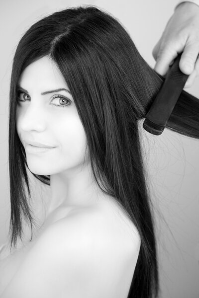 Black and white portrait of woman getting hair straightened