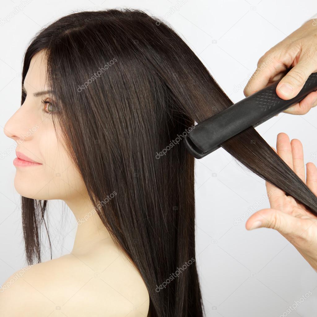 Woman getting hair straightened after trim at professional salon