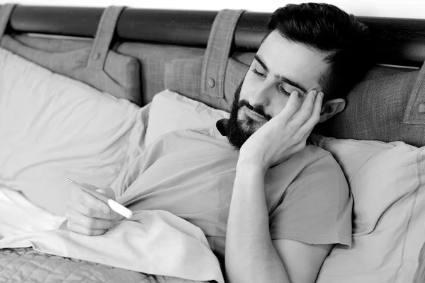 Black and white portrait of sick man in bed with fever — Stock Photo, Image