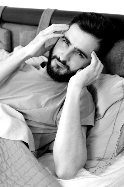 Man with strong headache lying in bed black and white portrait — Stock Photo, Image