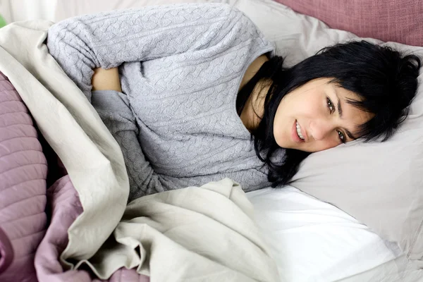 Γυναίκα με ισχυρή Εμμηνόρροιας πόνος στο στομάχι ξαπλωμένη στο κρεβάτι — Φωτογραφία Αρχείου