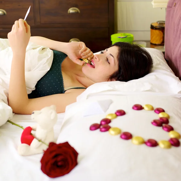 Vrouw omgeven door San valentijnskaartgiften en chocolade — Stockfoto