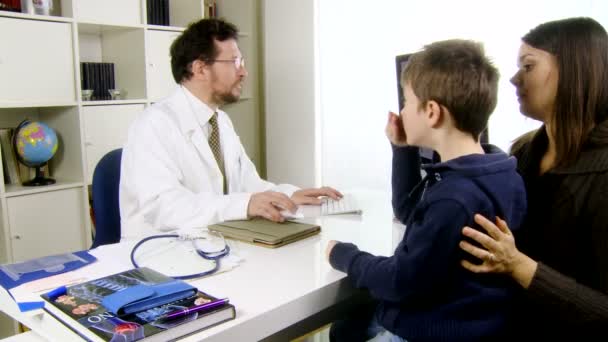 Врач разговаривает с ребенком и матерью в медицинской студии — стоковое видео