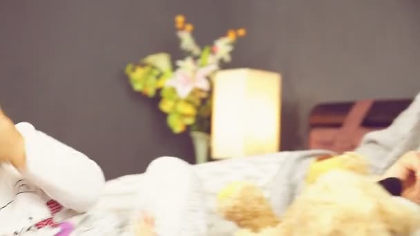 Маленькая девочка играет с матерью в постели крупным планом — стоковое видео