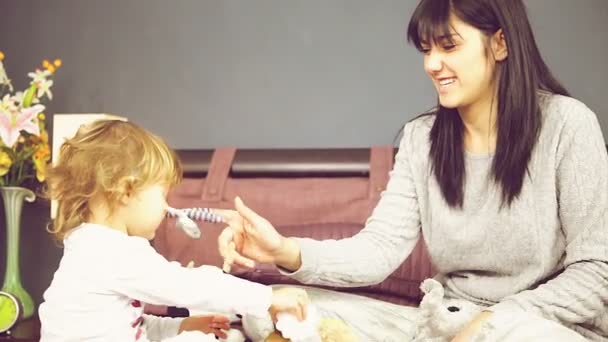 Gelukkig jonge moeder spelen in bed met een schattig klein meisje — Stockvideo