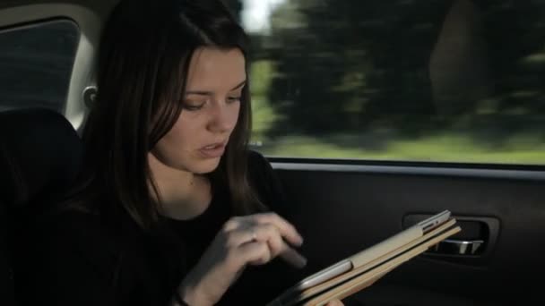 Деловая женщина работает на ipad, сидя в задней части автомобиля — стоковое видео