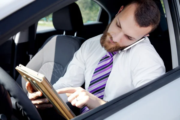 Obchodník s tabletu a telefonu v autě — Stock fotografie