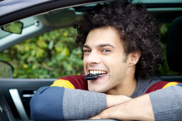 Šťastný muž s klíčem nové auto v ústech úsměv — Stock fotografie