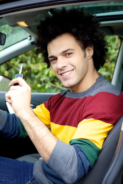 Jeune homme cool montrant la clé assis dans la voiture — Photo