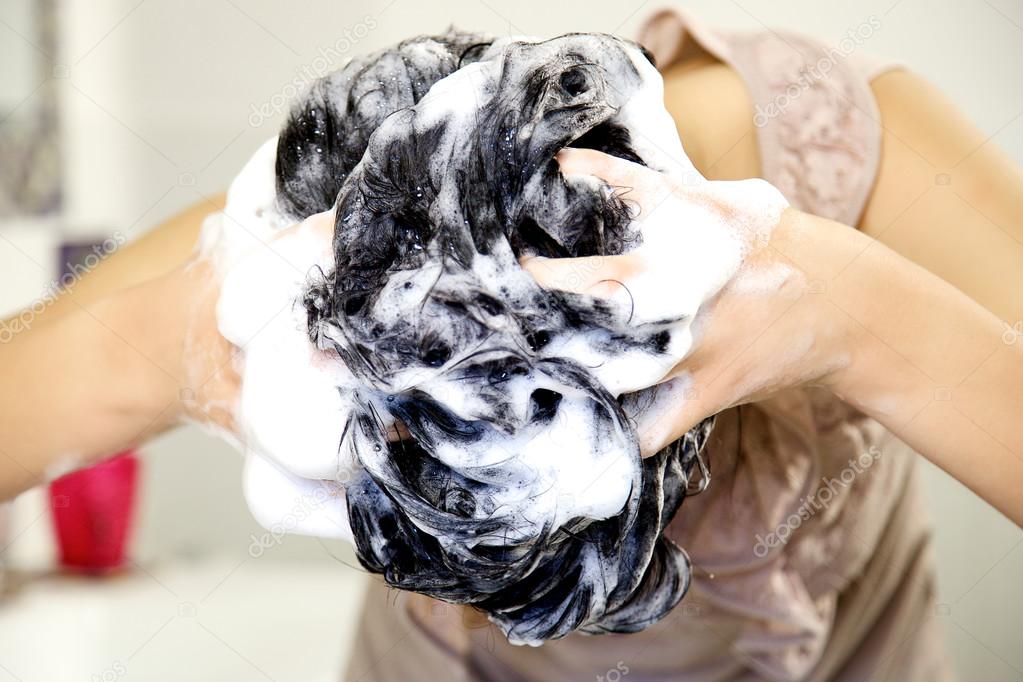 Closeup of head full of shampoo foam of girl washing