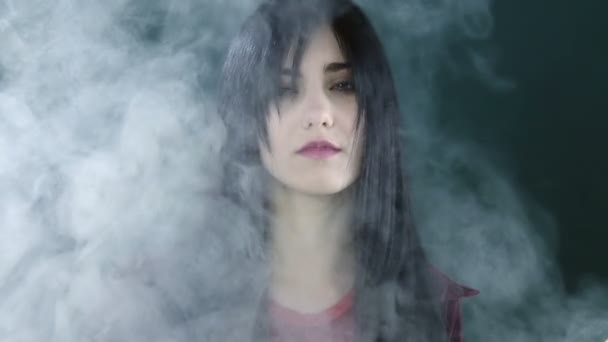 Retrato de una hermosa mujer saliendo de la niebla en el estudio — Vídeos de Stock