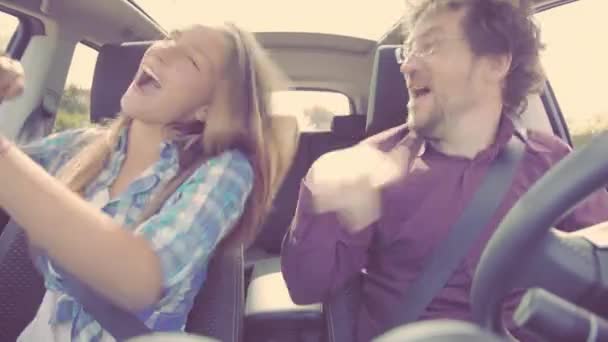 Man en vrouw dansen en zingen als een gek in de auto tijdens het rijden — Stockvideo