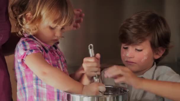Crianças se divertindo cozinhar um bolo ajudado pela mãe — Vídeo de Stock