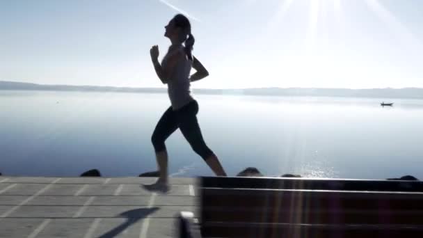 Caméra de course avec femme jogging en face du lac 4K — Video