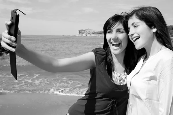 Dos mujeres jóvenes tomando selfie en frente de la playa haciendo caras divertidas retrato en blanco y negro —  Fotos de Stock