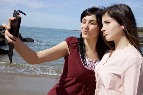 Dos mujeres jóvenes tomando selfie en frente de la playa haciendo caras divertidas —  Fotos de Stock