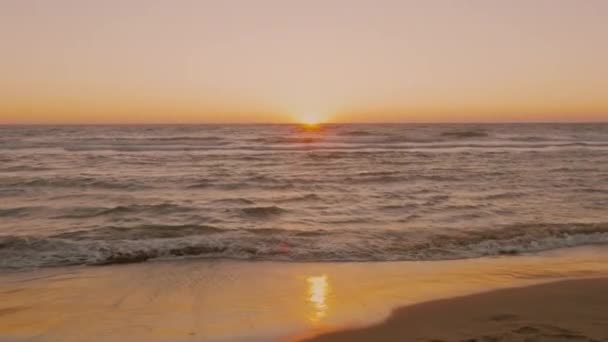 Mulher triste sentada em frente à praia pensando ao pôr do sol — Vídeo de Stock