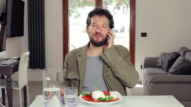 Hombre almorzando en casa hablando por teléfono — Vídeo de stock