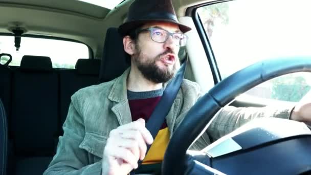 Счастливый человек в шляпе и с бородой за рулем, поющий — стоковое видео